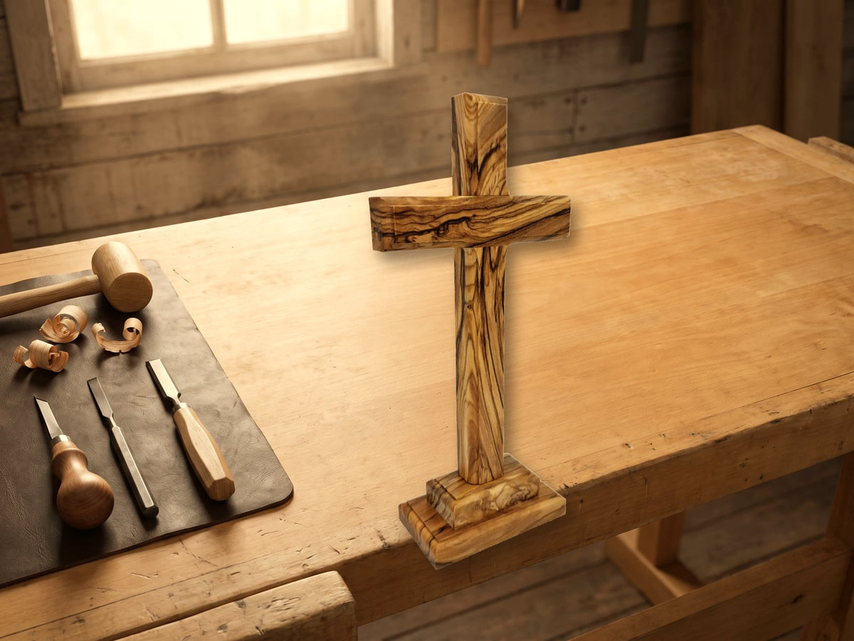 Cruz de pie de madera de olivo sobre un banco de trabajo con herramientas de grabado